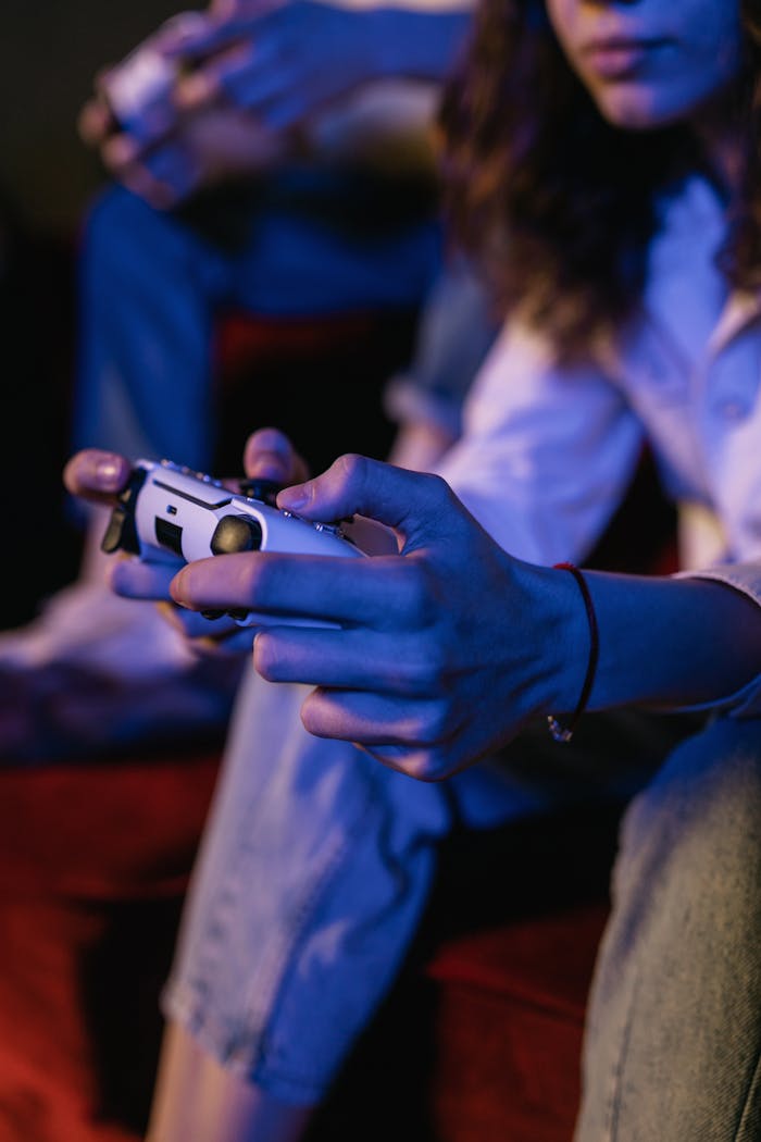 Two individuals focus intently on gaming with wireless controllers in a dimly lit room.